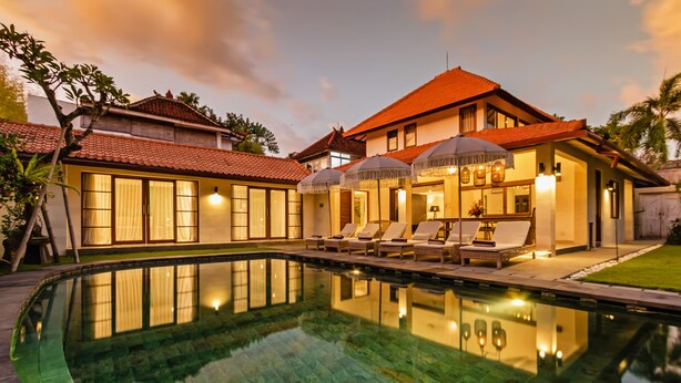 Um hotel com piscina, espreguiçadeiras e guarda-sóis.