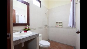 A bathroom with a sink, toilet, shower, and a mirror. - Grand Yuma Hotel & Villa (Denpasar)