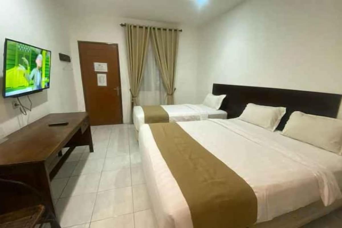 A hotel room with two beds, a TV, a desk, and a door.