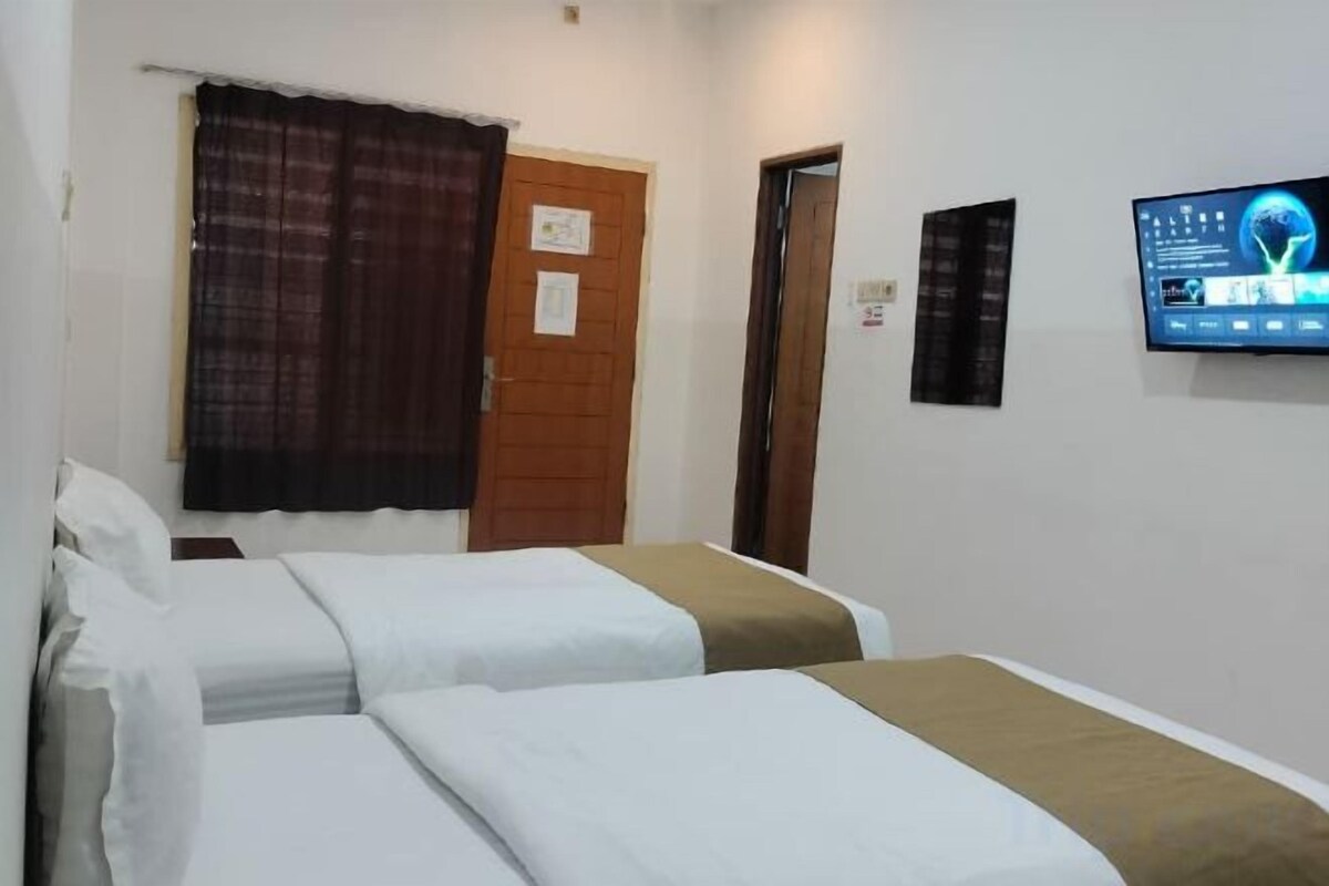 Une chambre d’hôtel avec deux lits, une télévision, une porte et un rideau.