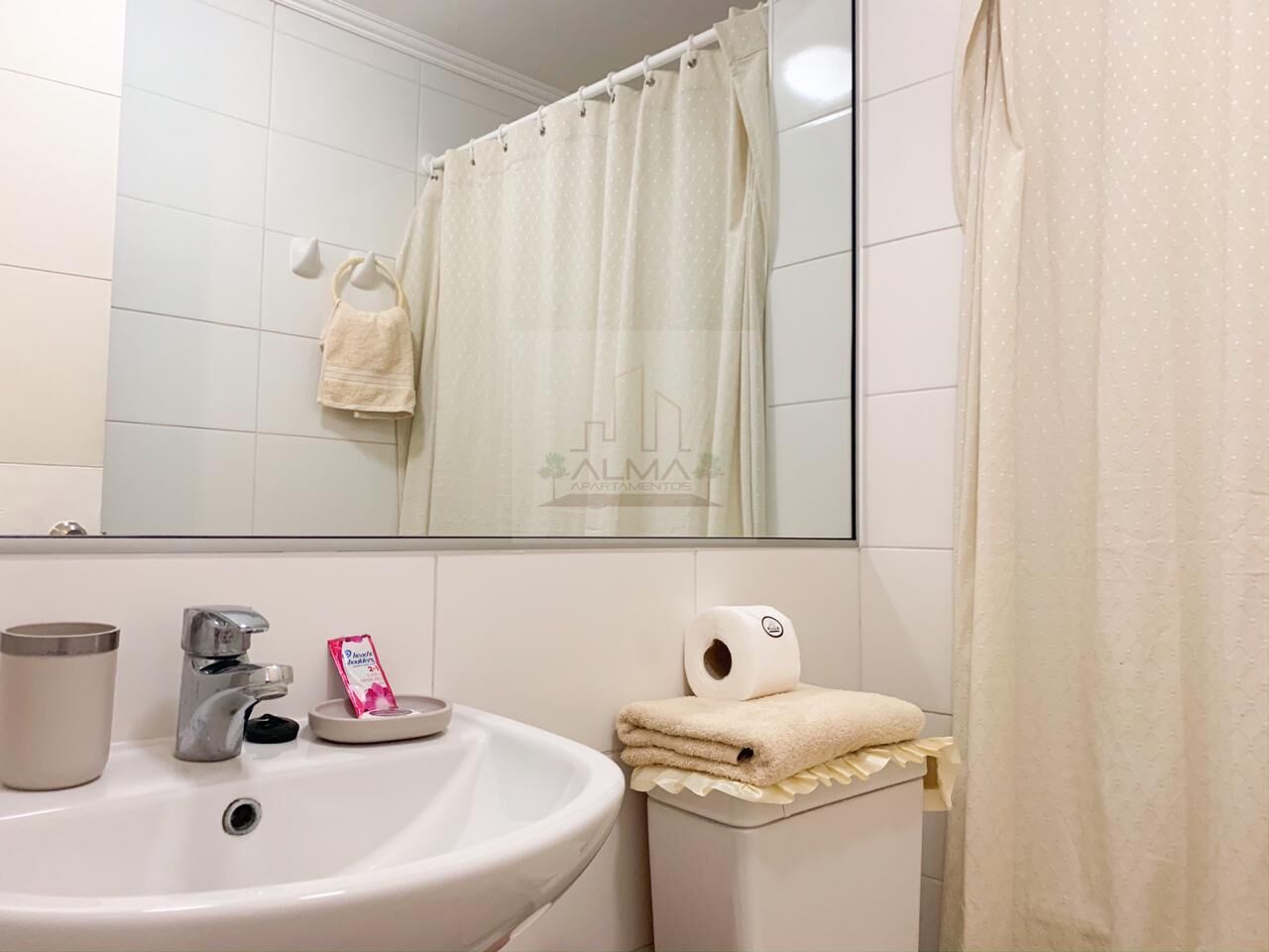 Un baño con lavabo, espejo y perchero para toallas.