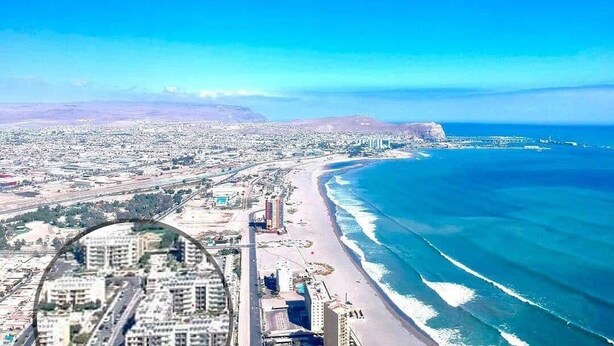 An aerial view of a coastal city with a beach, buildings, and a clear blue sky. - Apartment Alma Surire pool view (Arica)