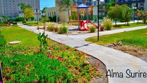 A hotel courtyard with a playground, palm trees, and a well-maintained garden. - Apartment Alma Surire pool view (Arica)