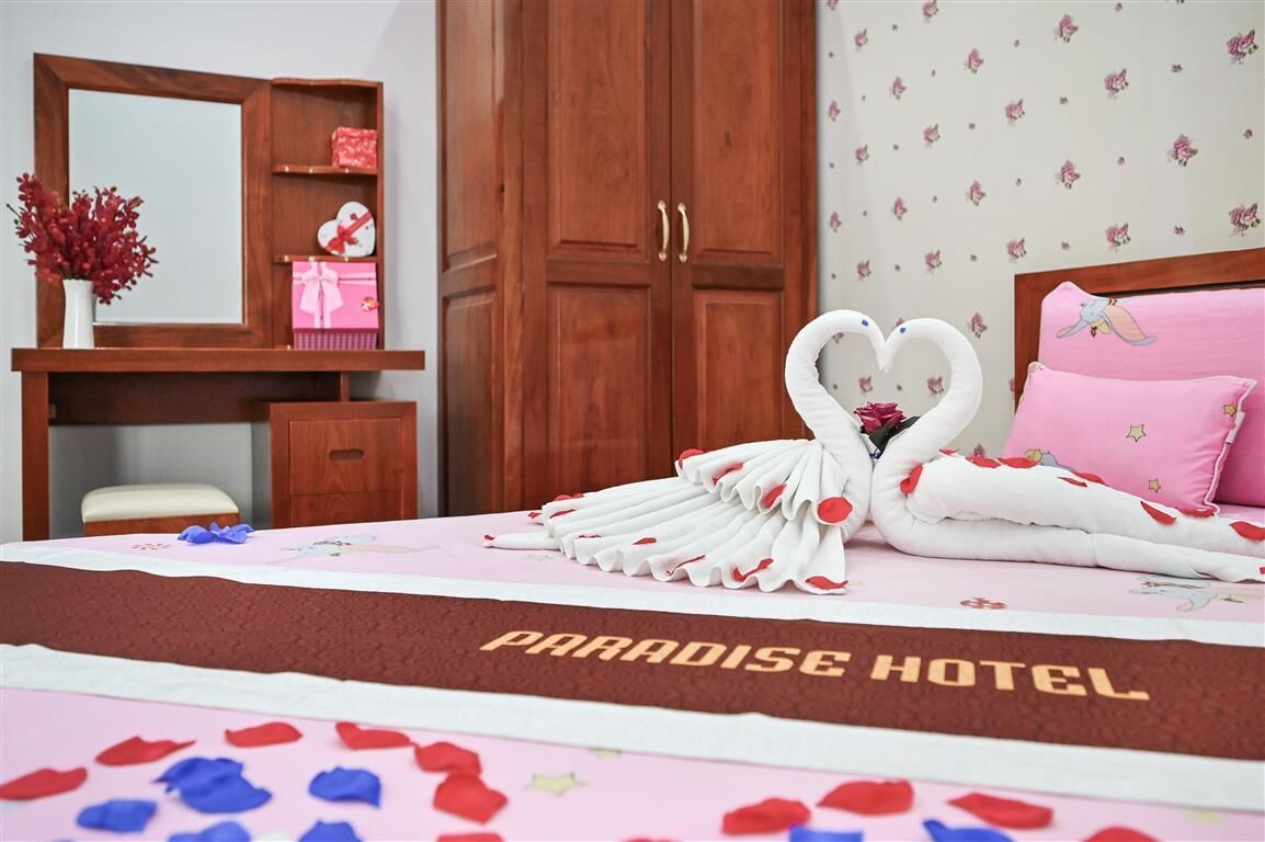 Habitación de hotel con cama, armario de madera, tocador con espejo y papel tapiz floral.