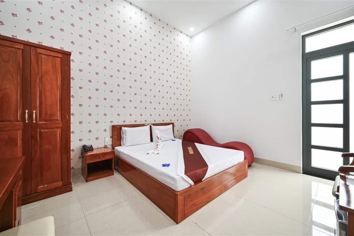 A bedroom with a wooden bed, a desk, and a wardrobe.