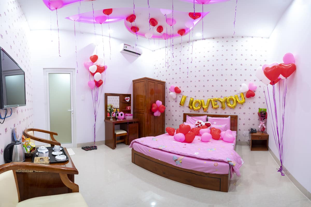 A bedroom with a bed, a desk, a wardrobe, and a television.