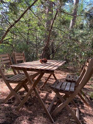 Ein Holztisch für ein Picknick mit vier Stühlen in einer bewaldeten Gegend.