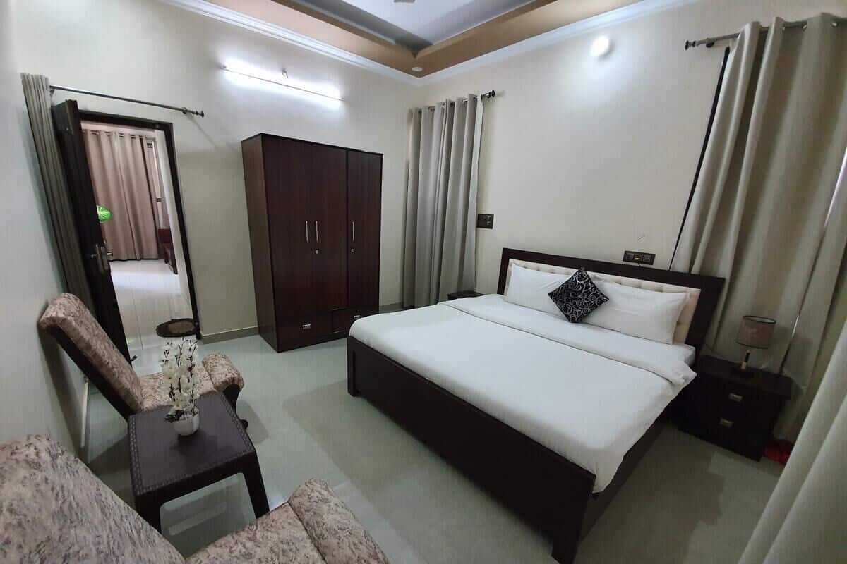 Ein Hotelzimmer mit Bett, Sessel, Nachttisch, Kleiderschrank und Spiegel.