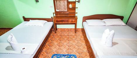 A room with two beds, a wooden nightstand with a mirror, and a blue floral rug.