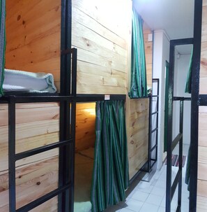 Een kamer met stapelbedden, houten wanden en een betegelde vloer.