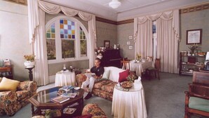 A spacious living room with a sofa, a coffee table, and a dining area with a table and chairs. - Forgandenny Bed & Breakfast (Mudgee)