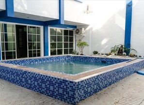A swimming pool with blue tiles, surrounded by a white building with blue accents and large windows. - 3BU Hostel La Union (San Fernando)