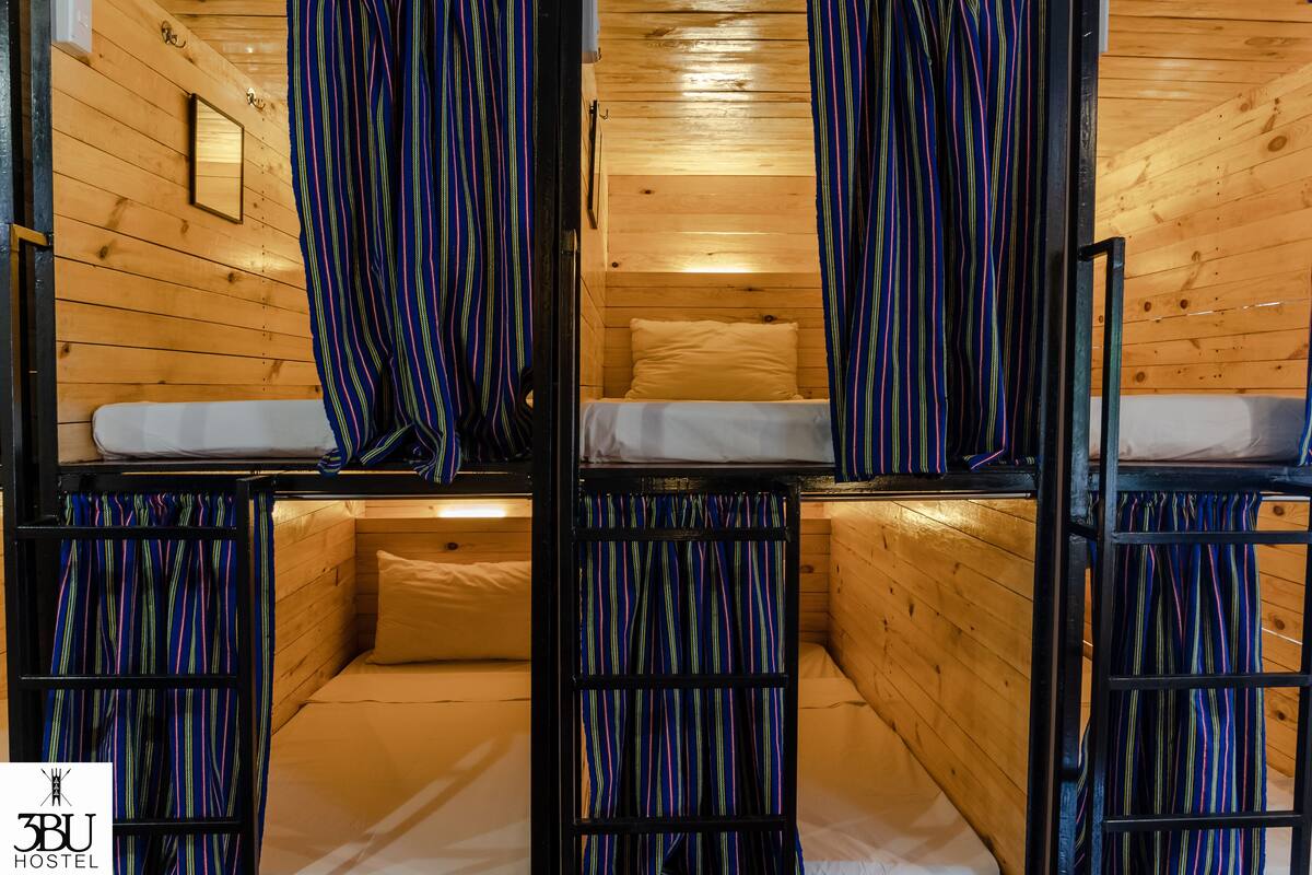 A cozy cabin-style room with bunk beds, wooden walls, and striped curtains.