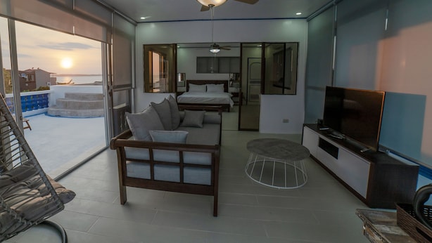 A modern living room with a sofa, TV, and ceiling fan. - 3BU Hostel La Union (San Fernando)