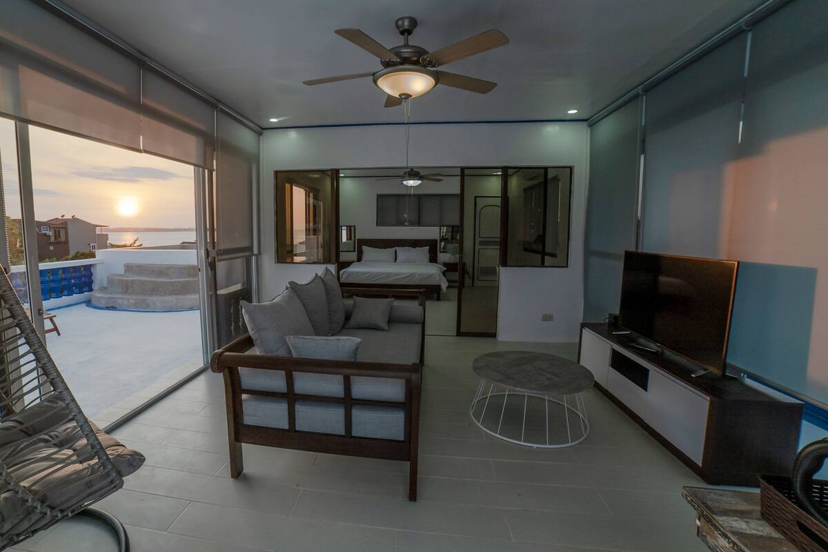 A modern living room with a sofa, TV, and ceiling fan.