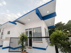 A modern building with a white exterior and blue accents, featuring a large glass door entrance and a small balcony. - 3BU Hostel La Union (San Fernando)
