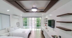 A modern hotel room with a large bed, a TV mounted on the wall, and a ceiling fan. - 3BU Hostel La Union (San Fernando)