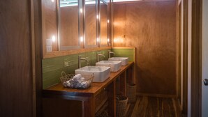 Un baño de madera con tres lavamanos, un espejo y un revestimiento de pared de azulejos verdes.