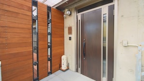 Un bâtiment moderne avec une façade en bois, une porte en verre et un petit espace extérieur agrémenté d’un banc.