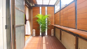 Un étroit couloir en bois, avec un pot de fleurs placé au centre, et de part et d’autre, deux piliers décoratifs.