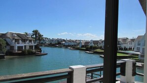 A waterfront property with multiple houses, a clear blue sky, and a calm body of water. - St Francis Bay House On The Canal (Saint Francis Bay)