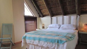 A bedroom with a bed, a chair, and a window with blinds. - St Francis Bay House On The Canal (Saint Francis Bay)