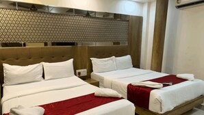 A hotel room with two beds, a patterned wall, and a wooden headboard.