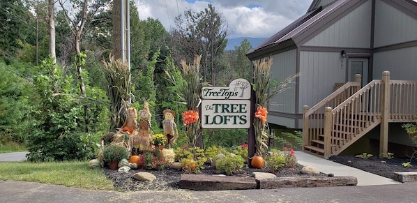 Un letrero que dice 'Tree Tops The Tree Lofts' con una escalera de madera que conduce a un edificio.