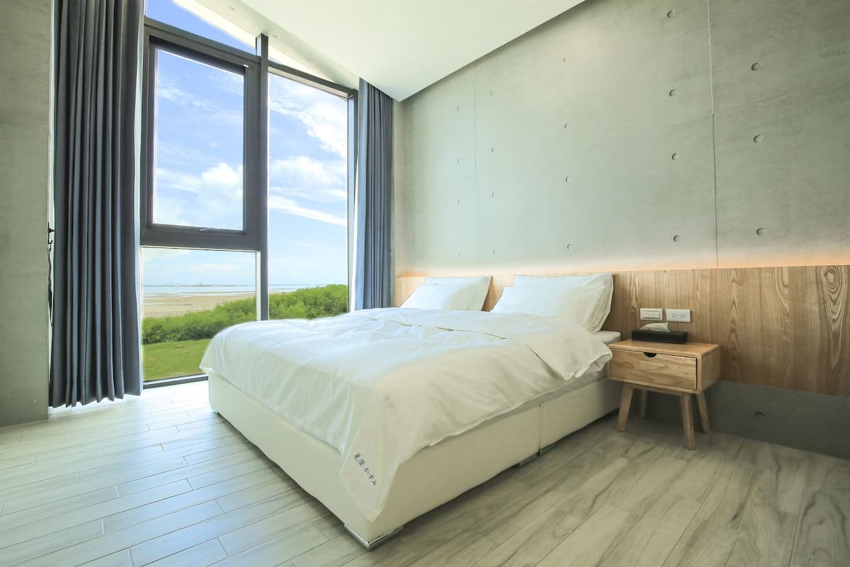 Een moderne slaapkamer met een groot bed, een houten nachtkastje en uitzicht op de omgeving.