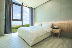 Un dormitorio moderno con una cama grande, una mesita de noche de madera y vistas al exterior.
