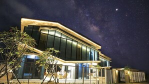 A modern house with large windows and a well-lit exterior at night.