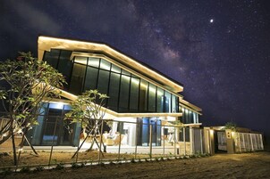 Una casa moderna con ventanas amplias e iluminación exterior en la noche.