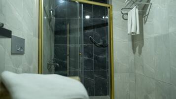 A bathroom with a glass-enclosed shower, a towel rack, and a toilet.