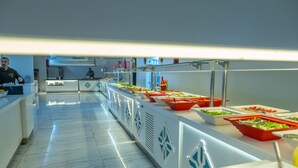 A buffet setup with various food stations and a person in the background.