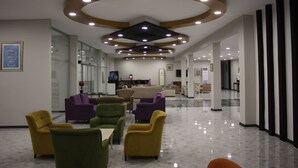 A spacious lobby with a modern ceiling design, comfortable seating, and a clean, polished floor.