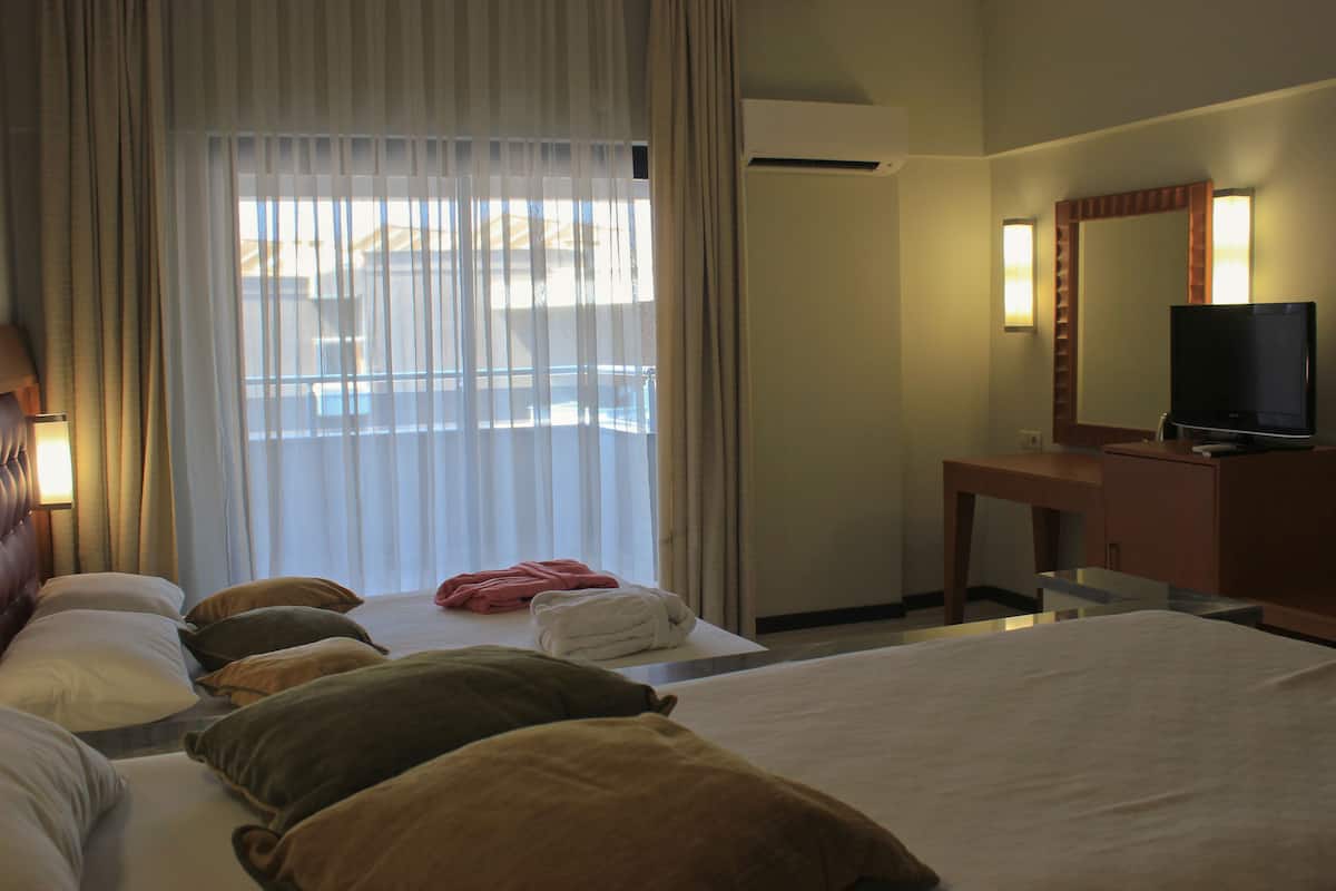 Une chambre d’hôtel avec un lit, un bureau, une télévision et une fenêtre avec des rideaux.