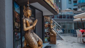 A statue of a seated figure in a public space with a staircase leading to an upper level.