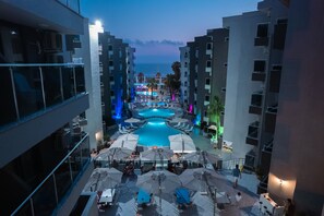 A rooftop pool area with lounge chairs and umbrellas, surrounded by modern buildings. - The Nora Hotels Family Club (Alanya)