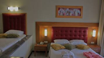 A hotel room with two beds, a headboard, bedside lamps, a painting, and a telephone on the nightstand.