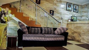 A lobby with a sofa, a staircase, and a reception desk. - Carabana Hotel & Suites (Uyo)