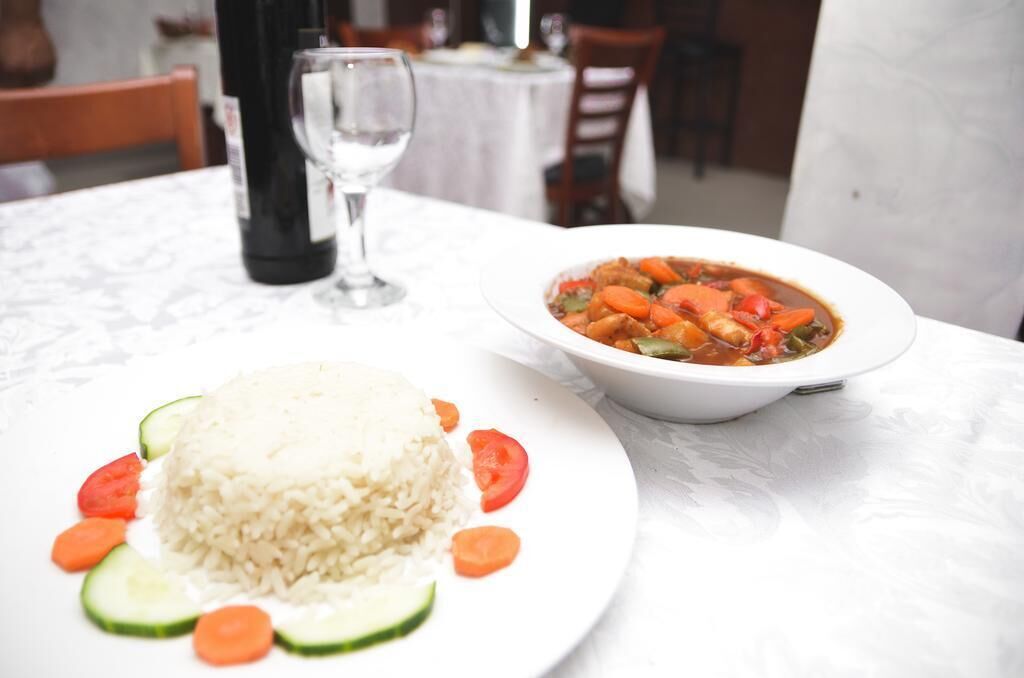 Una mesa con un plato de arroz blanco, verduras cortadas y un tazón de estofado.