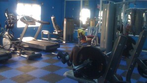 Une salle de sport équipée de matériel d’exercice, dotée d’un mur recouvert de miroirs et d’un sol à carreaux.