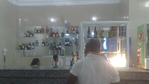 Un espace bar avec des étagères remplies de différentes bouteilles et un réfrigérateur.