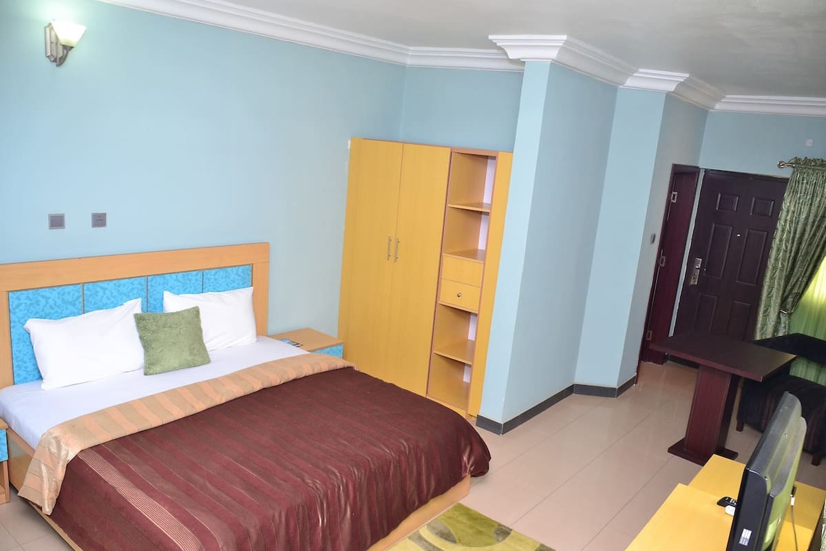 Une chambre à coucher comprenant un lit, une armoire, un bureau et un téléviseur.