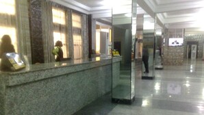 Un espace d’accueil d’hôtel comprenant un comptoir en marbre, un bureau d’accueil et une cloison en verre.