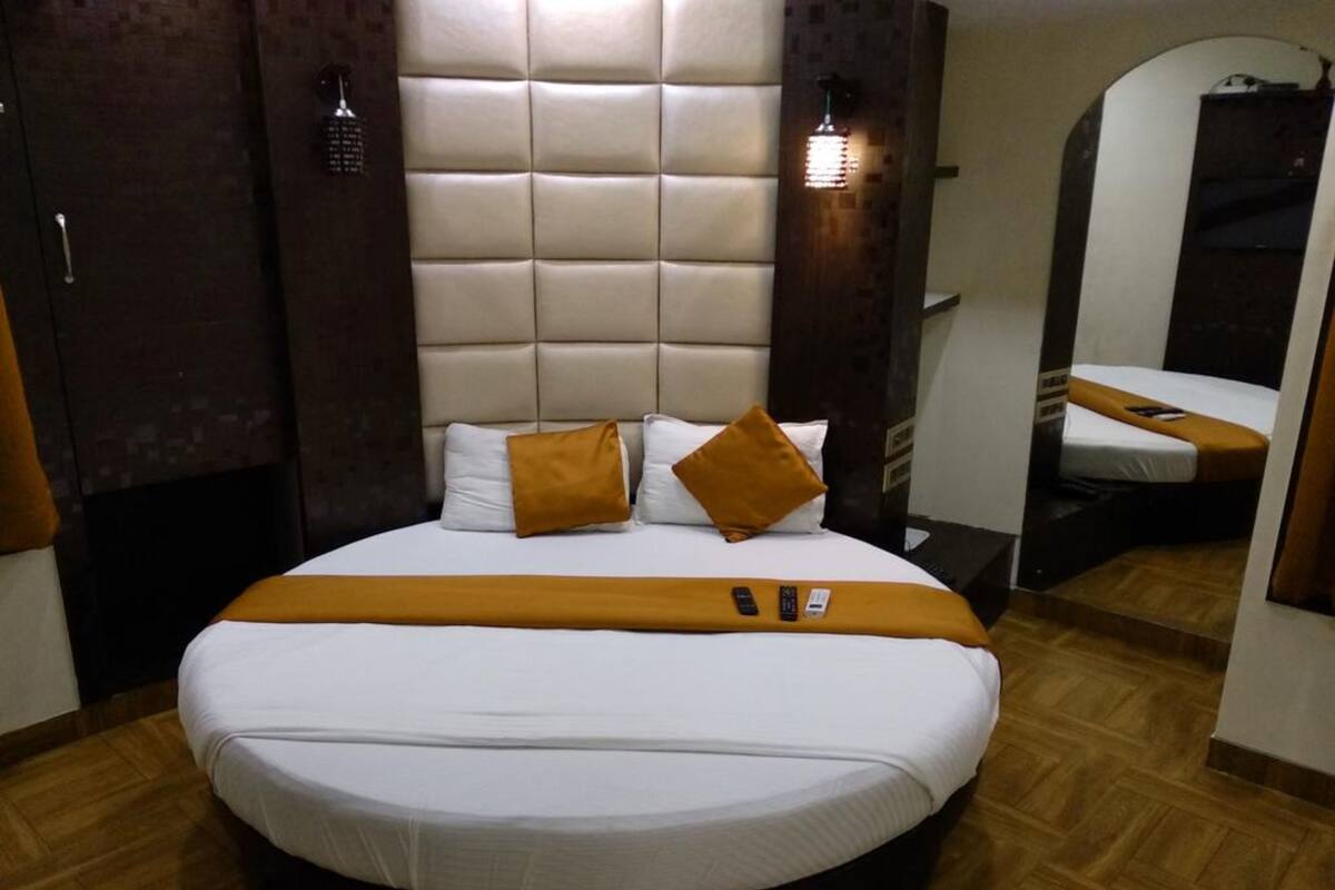 Une chambre d’hôtel avec un grand lit, une tête de lit et un miroir.