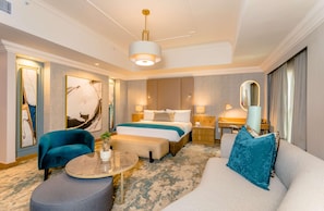 A modern hotel room with a large bed, a sofa, a chair, a small table, and a desk. - Southern Sun Sandton (Johannesburg)