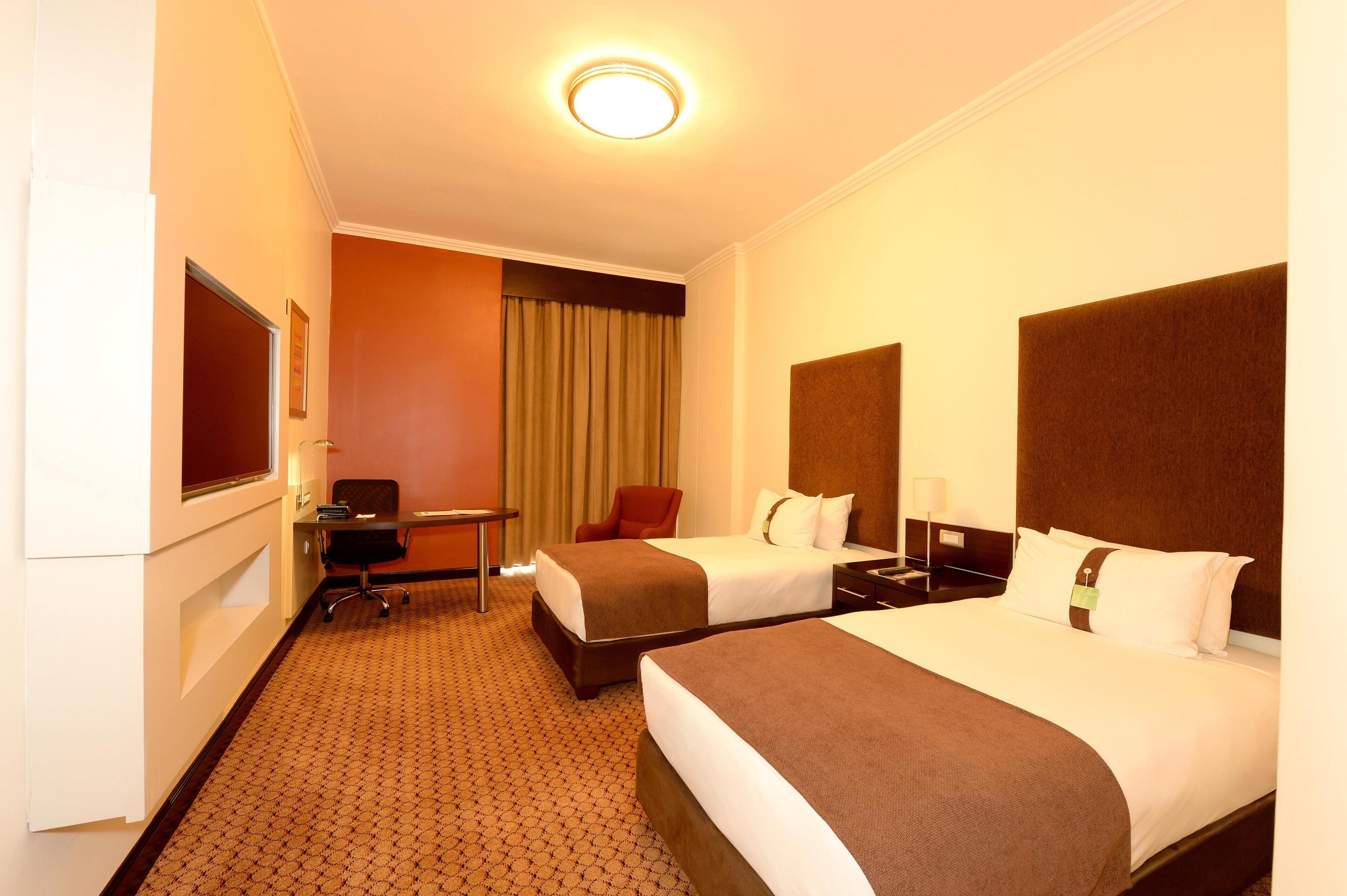 Een hotelkamer met twee bedden, een bureau, een stoel en een televisie.