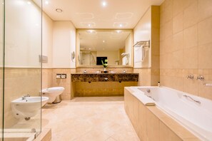 A modern bathroom with a large mirror, a bathtub, a sink, and a toilet. - Southern Sun Sandton (Johannesburg)