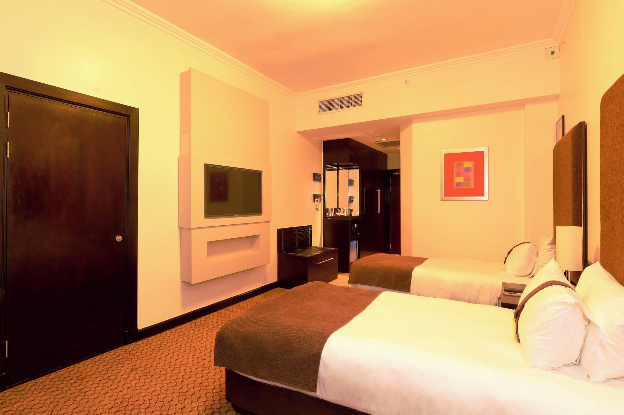 A hotel room with two beds, a television, a desk, and a wardrobe.